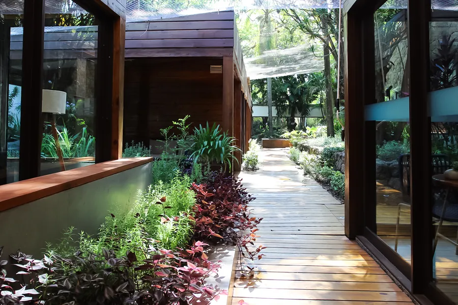 Jardim interno com deck de madeira e muros de pedra