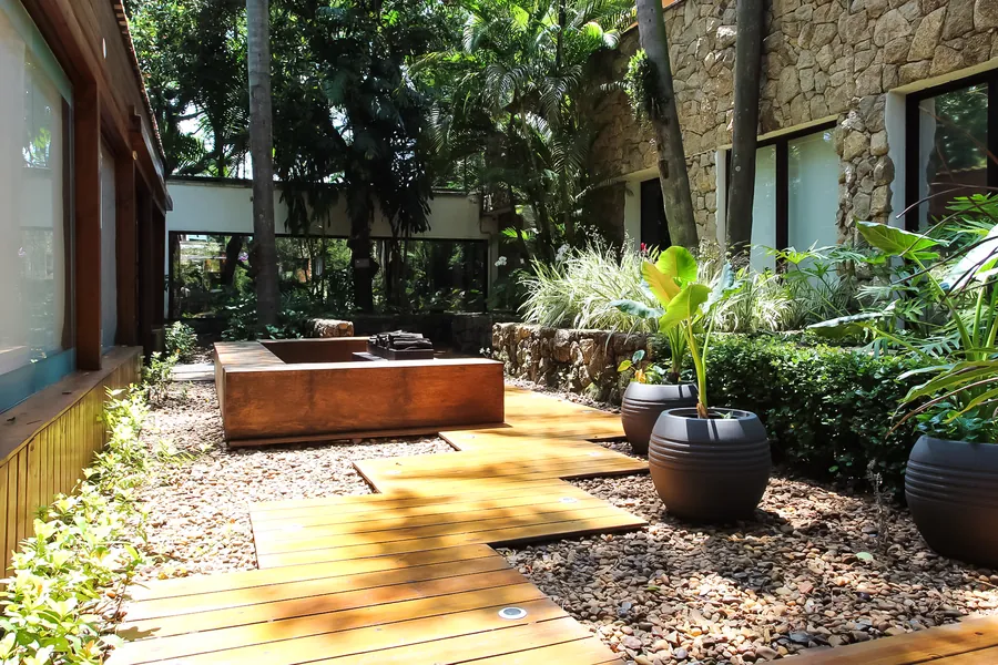 Deck de madeira e vasos com plantas ao lado do prédio de pedra